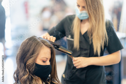 Woman with facemask getting her hair done at the beauty salon
