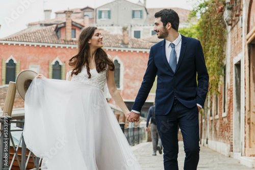 Young married couple roaming in the city doing photoshoot in wedding outfits