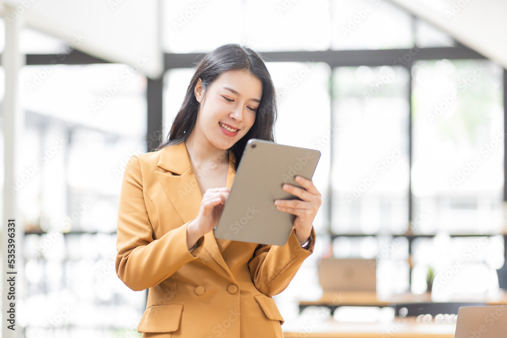 Successful Business Asian woman in Stylish Dress Using Tablet Computer, Standing in Modern Office Working on Financial, Business and Marketing Projects. Portrait of Beautiful Asian Manager.
