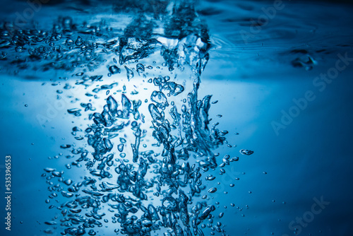 An abstract background created by air bubbles in water under blue lighting.