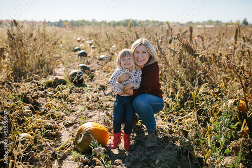 mom and daughter smiling together in a pumpkin patch