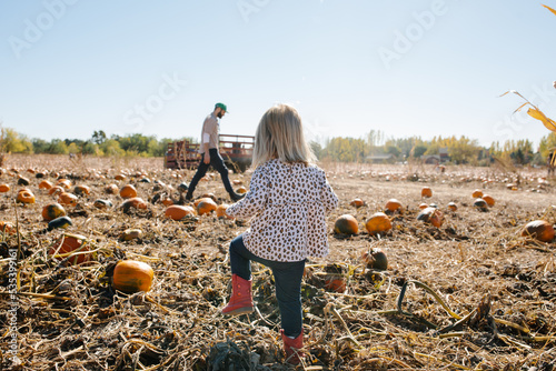 father and daughter walking through a pumpkin patch together