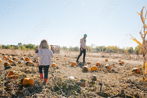 father and daughter walking through a pumpkin patch together