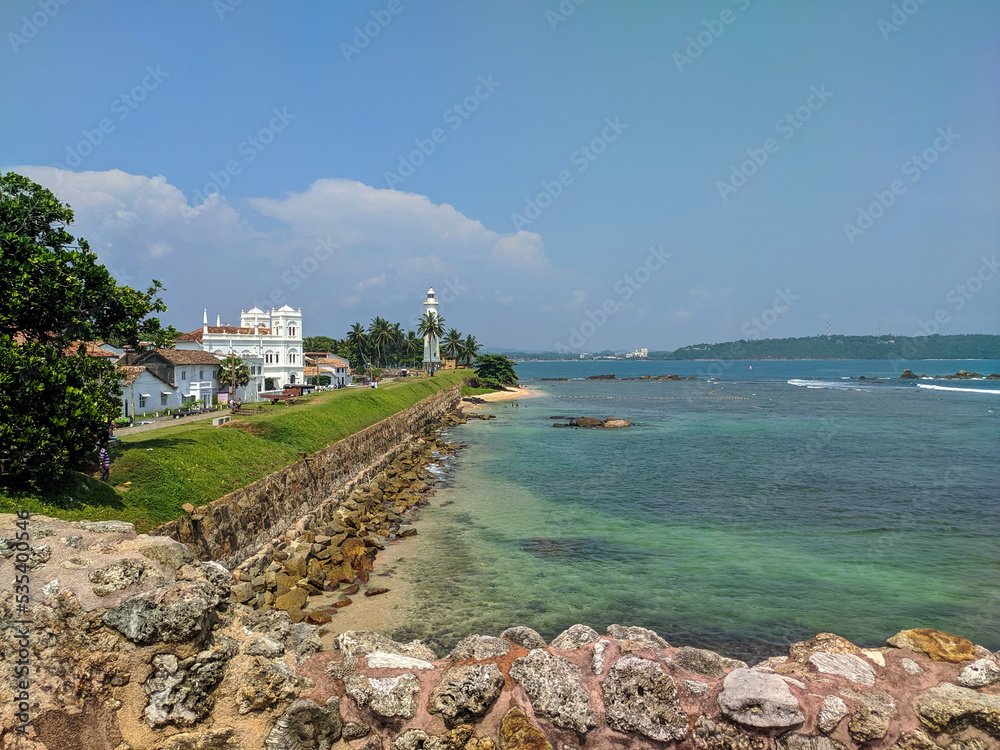 Φωτογραφία Galle, Sri Lanka - March 12, 2022: View of the white stone lighthouse and the fortress wall along the ocean in Galle Fort