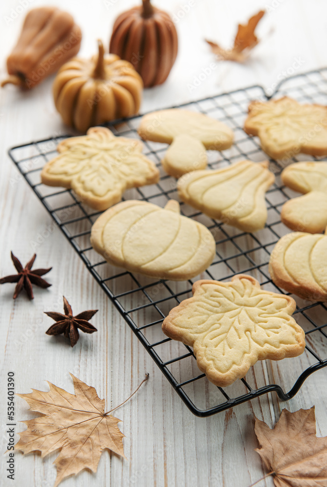 Cookies shaped like pumpkin and leaves on rustic wood background