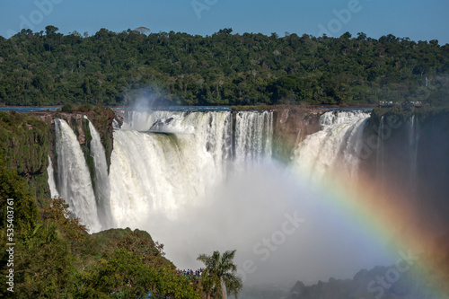 A rainbow forms at the Iguazu Falls looking from the Brazilian side towards Devil s Throat. The Iguazu Falls border both Brazil and Argentina.
