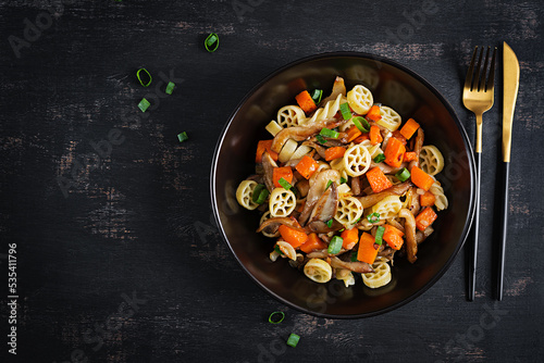 Rotelle pasta gluten free with mushrooms and pumpkin on a dark background. Vegetarian, vegan  food. Italian cuisine. Top view