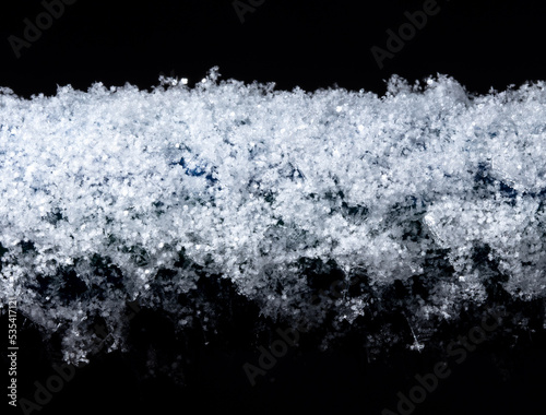 White snowflakes on a tube in winter isolated on a black background.