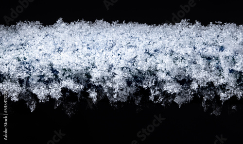 White snowflakes on a tube in winter isolated on a black background.