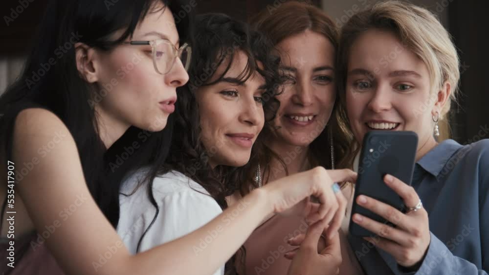 Slow motion medium close-up of modern bride, her mom and friends watching something funny on smartphone Slow motion medium close-up of modern bride, her mom and friends watching something funny on smartphone