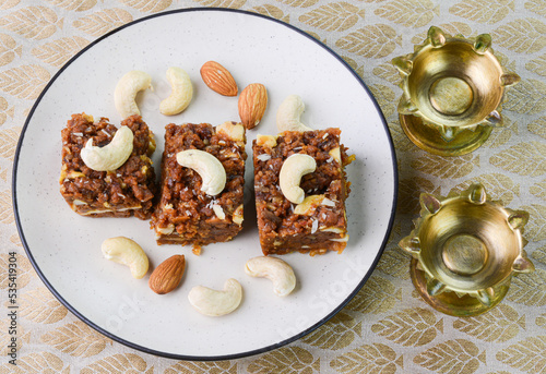 Dodha barfi sweet dish with diya oil lamps in the background. photo