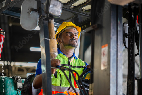 Worker man in hardhat and safety vest driving forklift for control loading box, Warehouse forklift loader works with goods