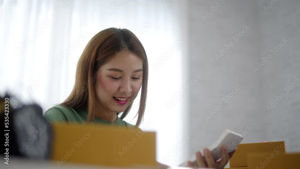Young owner business woman received orders from clients and preparing products in parcel cardboard box packaging at home. Young owner business woman received orders from clients and preparing products in parcel cardboard box packaging at home.