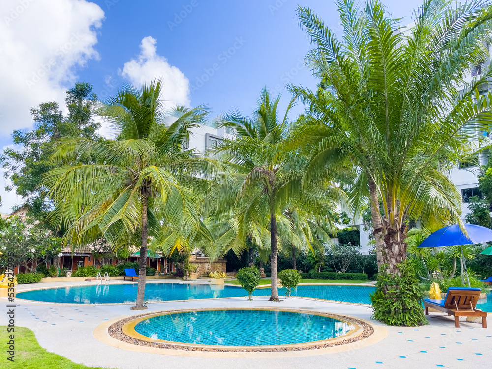 Kids swimming pool next to big one with green palm trees on hotel resort. Summer vacation, tropical destination concepts