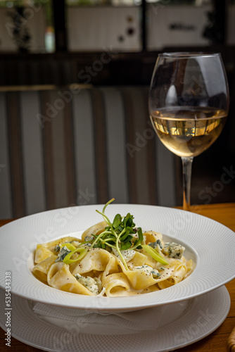 delicious pasta with cheese, greens, sauce in a restaurant 
