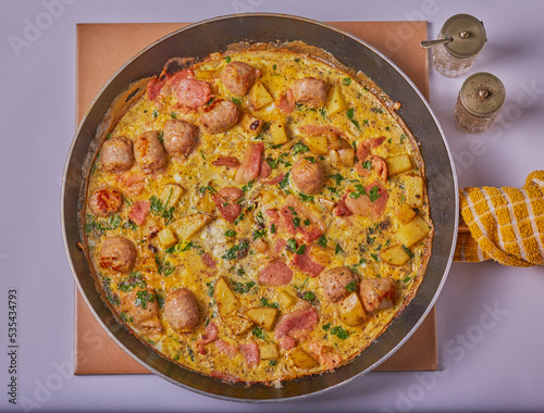 Italian styled bacon,sausage and potato frittata resting in a pan.