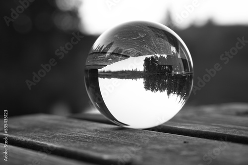 Glass ball on a wooden pier at a Swedish lake at dusk in black and white. Nature photo