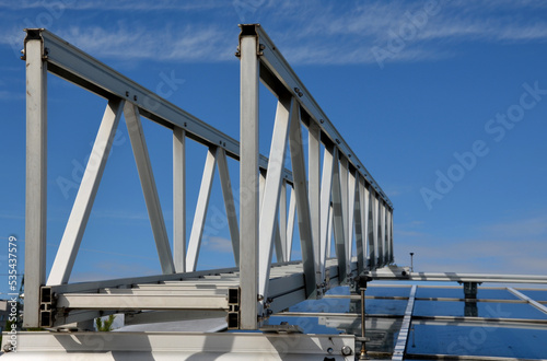 aluminum footbridge for washing windows above the skylight. simplifying the washing of large greenhouses and galleries with ceiling windows. the ladder can be moved over the rails, blue sky, trowel © Michal