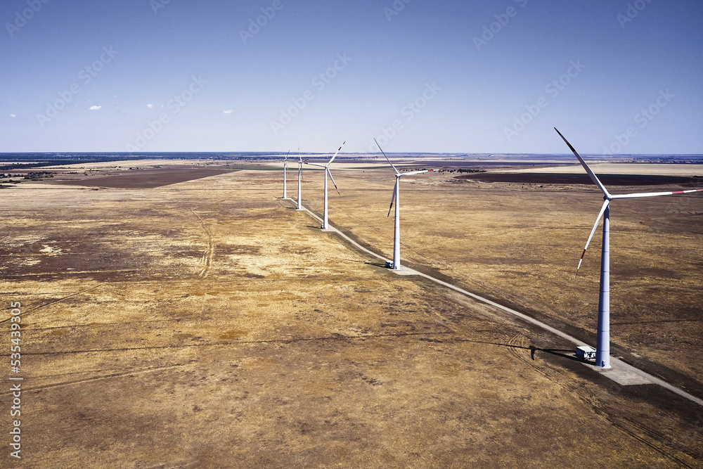 wind power plant in the steppe against the blue sky shooting from a drone