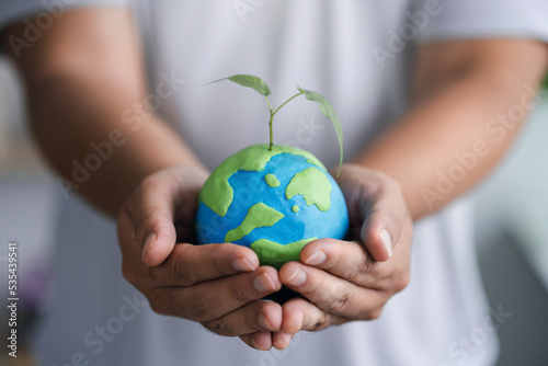 Fototapeta Naklejka Na Ścianę i Meble -  man holding a globe with a green sapling love the world concept love the world concept sprouts grow above the earth new life, environment, sustainable life, zero waste, plastic free, earth day,