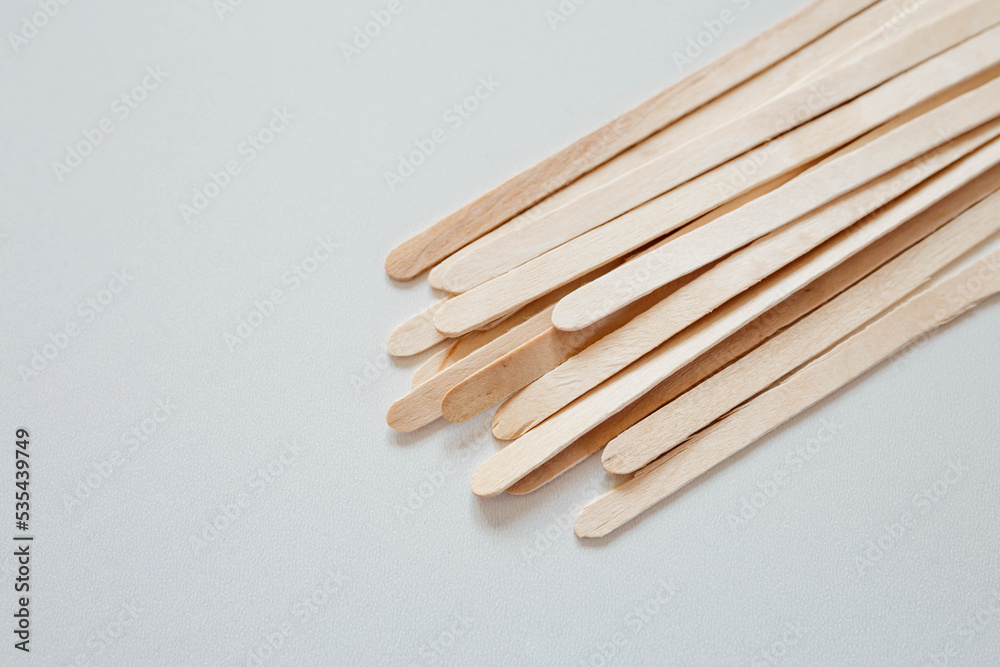 Materials for depilation of eyebrows and delicate areas. Wooden sticks lie on a white background