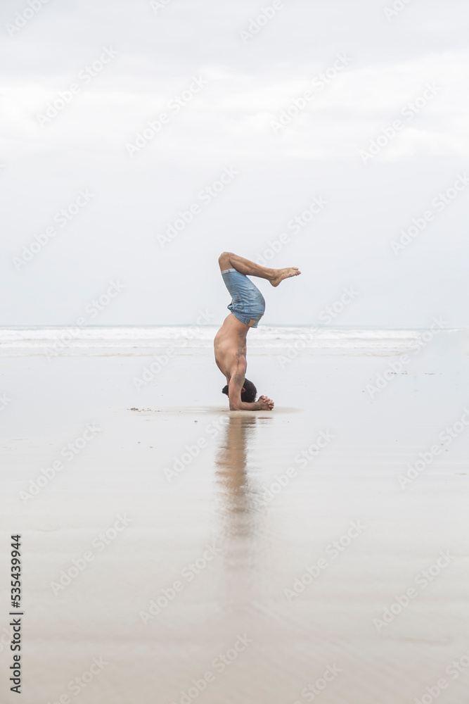 Caucasian man doing yoga poses on the sand by the sea. Caucasian man doing yoga poses on the sand by the sea.