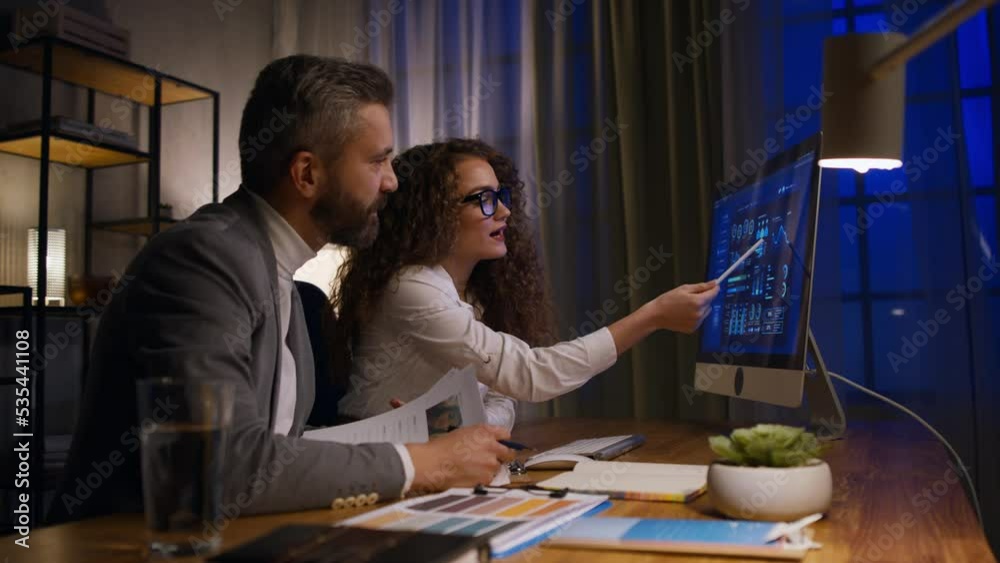 Young woman working with her colleague in office during evening, consulting something. Young woman working with her colleague in office during evening, consulting something.