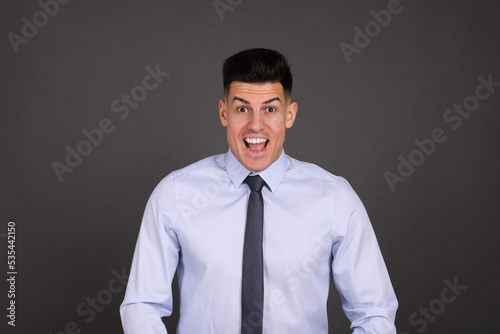 Portrait of happy businessman on dark grey background. Personality concept