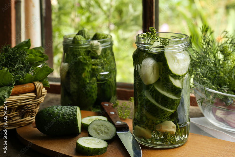 Glass jars, fresh cucumbers and herbs on wooden table indoors. Pickling recipe Glass jars, fresh cucumbers and herbs on wooden table indoors. Pickling recipe