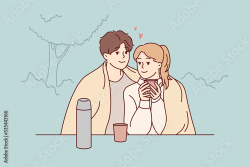 Happy couple sitting in park hugging drinking warm coffee enjoy romantic date together. Smiling loving man and woman embrace cuddling outdoors. Vector illustration. 