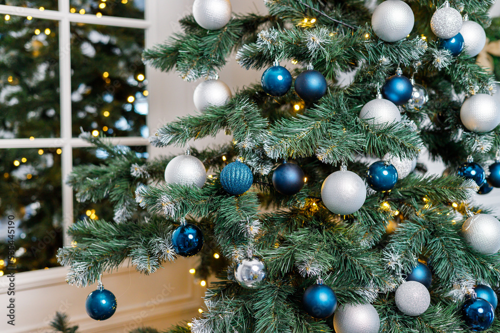 Christmas tree with blue and silver toys. Festively decorated Christmas tree with garlands. Symbol of the new year. Christmas tree with blue and silver toys. Festively decorated Christmas tree with garlands. Symbol of the new year.