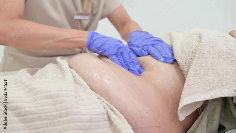 Beautician applying gel on fat abdomen of client Beautician applying gel on fat abdomen of client