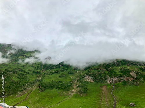 Green grassy slopes and white clouds falling from sky