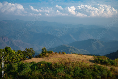 blue sky landscape with clouds. top of mountain before sunset time.  layers of hill background. scenery view wallpaper. mixed forest and prairie area.