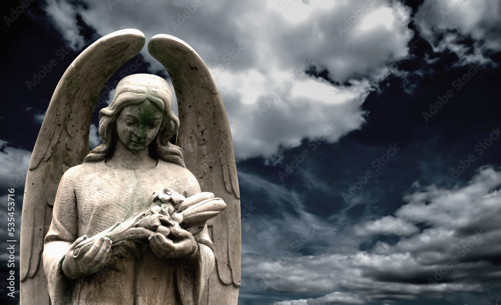 An ancient statue of guardian angel against dramatic view of cloudy sky. Copy space. An ancient statue of guardian angel against dramatic view of cloudy sky. Copy space.