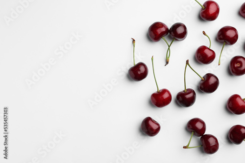 Many sweet ripe cherries on white background, flat lay. Space for text