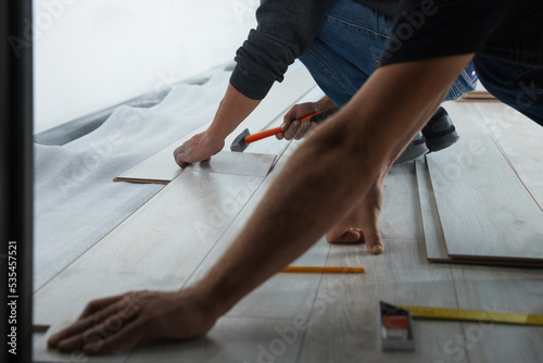 Workers installing new laminated flooring in room, closeup