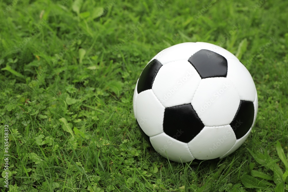 Football ball on green grass outdoors, space for text Football ball on green grass outdoors, space for text