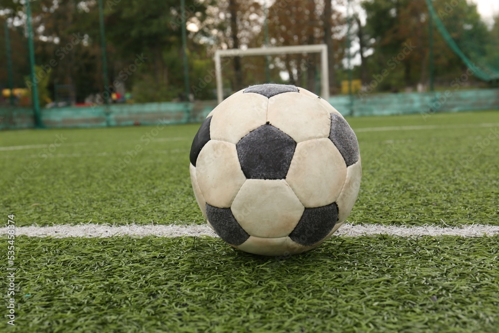 Fototapeta premium Dirty soccer ball on green football field