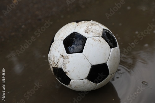 Dirty soccer ball near puddle outdoors  closeup