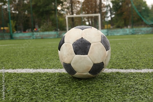 Dirty soccer ball on green football field