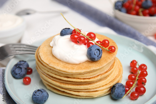 Tasty pancakes with natural yogurt, blueberries and red currants on table, closeup