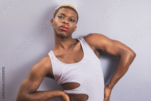 An african young man posing on a purple background, androgynous man concept. photo