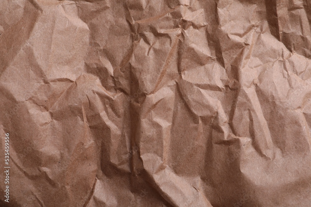 Fototapeta premium Texture of wrinkled kraft paper bag as background, closeup
