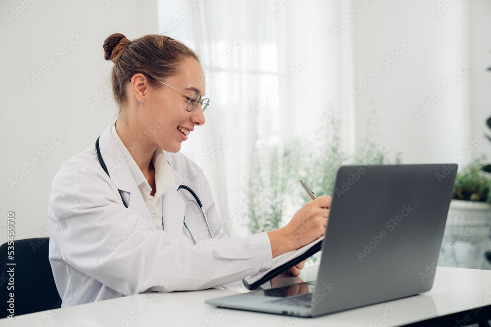 Woman doctor in uniform greeting patients online on laptop during on line meeting. Woman doctor in uniform greeting patients online on laptop during on line meeting.