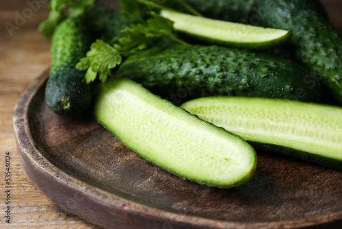 Fresh ripe cucumbers and parsley on wooden table, closeup