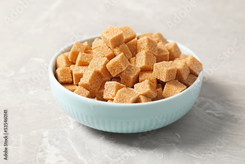 Brown sugar cubes in bowl on light grey marble table