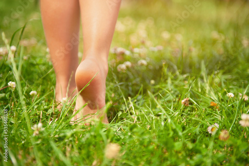 Child walking barefoot on green grass outdoors, closeup. Space for text