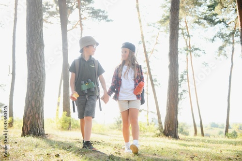 Little boy and girl go hiking on a forest road