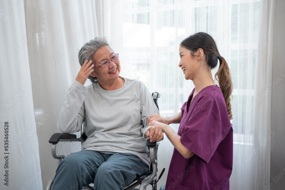 Asian young nurse taking care and talking mature female patient sitting on wheelchair in hospital. Healthcare concept. Asian young nurse taking care and talking mature female patient sitting on wheelchair in hospital. Healthcare concept.